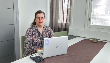 Terhi Lehtinen istuu pöydän ääressä ja pöydällä on kannettava tietokone