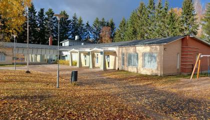 Keltainen rakennus, taustalla metsää.