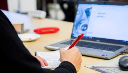 Henkilö kirjoittaa muistiota.