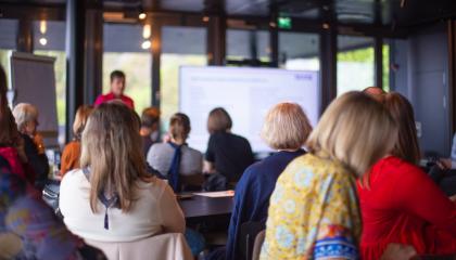 Asiantuntijayleisö kuuntelee ja katsoo esitystä.