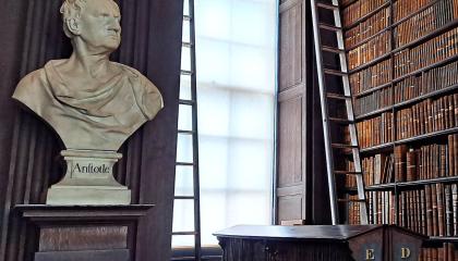 Kirjastorakennus, jonka toisella seinällä on runsaasti kirjoja ja vasemmalla reliefi.