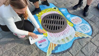 Kaupungin työntekijät asettelevat kalatarraa katukaivon ympärille.