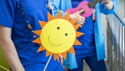 Siniseen paitaan pukeutunut henkilö pitelee auringon muotoista viiriä.