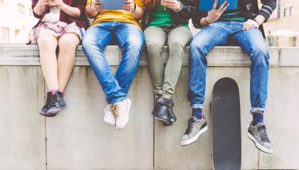 Nuoria ihmisiä istumassa aidalla.