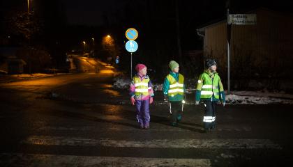 Lapset ylittämässä suojatietä heijastinliivit päällään.