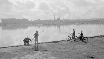 Mustavalkoisessa valokuvassa kaksi onkijaa Ratinan suvannolla, ja kaksi poikaa pyörien selässä katselemassa ongintaa.