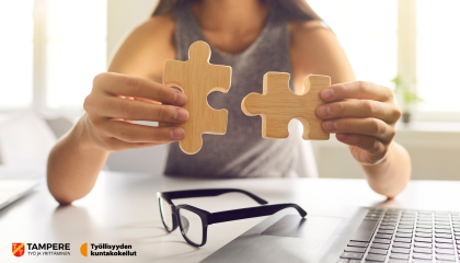 Nainen istuu pöydän ääressä. Hän sovittaa kahta isoa palapelin palaa käsissään yhteen.