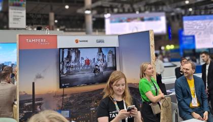 Ihmisiä seisoo messuosastolla. 