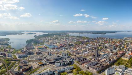 Tampereen kaupunkialue ilmasta käsin kuvattuna, etualalla tiivistä kaupunkia ja taustalla siintää järvimaisema.