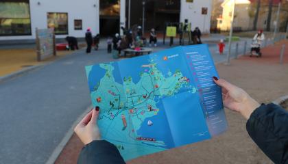 Seikkailukartta lähikuvassa, taustalla päiväkodin pihassa vilskettä.