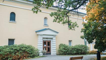 Keltainen vanha rakennus vehreässä ympäristössä.