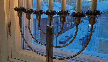 Seitsenhaarainen joulukynttelikkö ikkunalla.