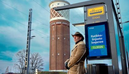 Cowboy-hattuinen mies odottaa ratikkaa Tehtaan pysäkillä Hiedanrannassa.