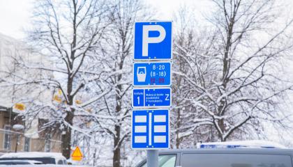 Kuvassa talvinen maisema, lumisia puita, autojen kattoja ja P-merkki Keskustorilla.