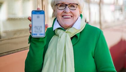 Nainen näyttää puhelimestaan mobiililippua ratikan edessä.