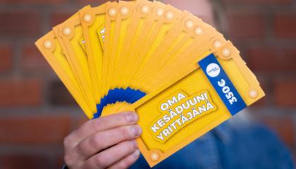 Henkilön ojennetussa kädessä on viuhkan muotoisena nippu seteleitä, joissa lukee Oma kesäduuni yrittäjänä sekä summa 350 euroa. Seteliviuhka peittää henkilön kasvot. 