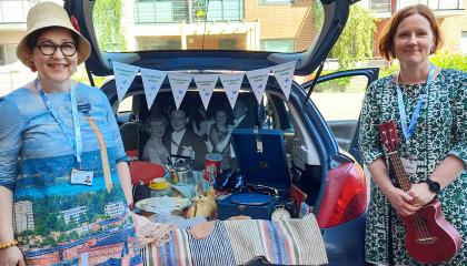 Kaksi naista seisoo avonaisen auton tavaratilan äärellä.