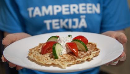 Lautasella vohvelin, jonka päällä on kurkkua ja tomaattia