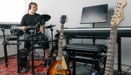 Henkilö soittaa sähkörumpuja, edustalla muitakin soittimia.