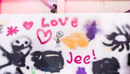 Iloisen näköisiä hahmoja, sydämiä, aurinko ja sanat &quot;Love&quot; ja &quot;Jee&quot; graffitiseinällä.