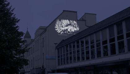 Havainnekuva katunäkymästä, jossa talon seinälle on heijastettu muumikuvitus.