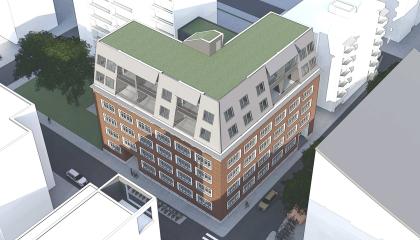 Kuvassa punatiilinen rakennus ja korotuskerros ilmakuvaperspektiivistä.