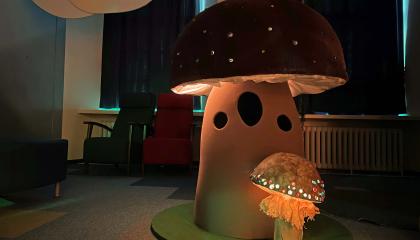 Iso ja pieni käsin tehty sieni, joiden hatut hohtavat valoa. 