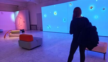 Ihmishahmo seisoo sinisävyisessä galleriatilassa katsomassa taideteosta.