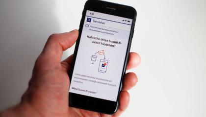 Ihmisen kädessä matkapuhelin, jonka näytöllä ohjeistetaan, miten voi ottaa käyttöönsä suomi.fi-viestit.