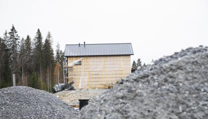 Sorakasan takaa näkyy keskeneräisen omakotitalon rakennustyömaa metsikön laidalla.