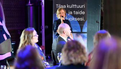 Karoliina on mikrofoni kädessään puhumassa uudistuneen Kulttuuripankin julkistamistilaisuudessa 30.9.2025