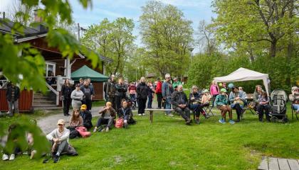 Iso joukko ihmisiä istuu ulkona odottamassa tapahtuman alkua. 