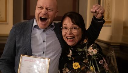 Kaksi henkilöä juhlistaa iloisesti saamaansa palkintoa. 