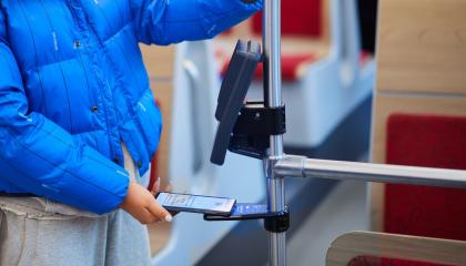 Matkustaja näyttää mobiililippunsa ratikan lukulaitteelle.