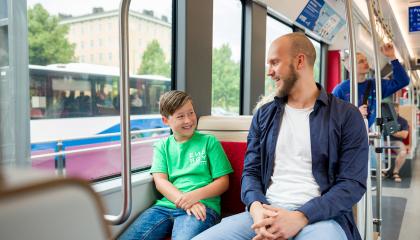 Mies ja poika istuvat bussissa, jonka ikkunasta näkyy toinen bussi.