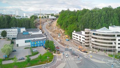 Kuvassa katu, jossa työmaa. Ympärillä rakennuksia ja vihreyttä.