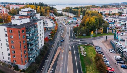 Kuvassa raitiotietyömaa, katua, taloja ja pysäköityjä autoja. 