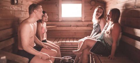  Four people enjoying löyly in Suolijärvi sauna at city of Tampere, the international sauna capital of the world. 