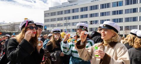 A crowd of students in student caps blowing soap bubbles.