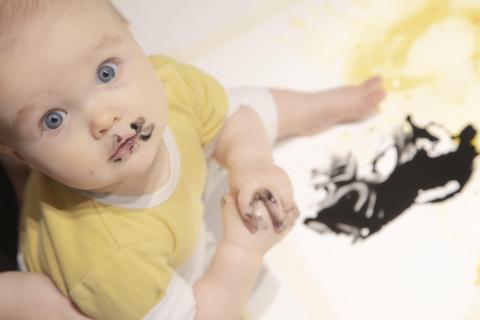 A baby paints a work of art in black colour.