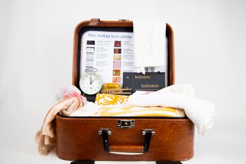 Avonaisen matkalaukun sisällä on lakanoita, papiljotit ja herätyskello.