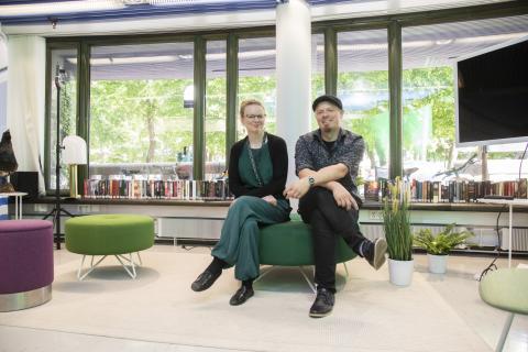 Kaksi ihmistä istuvat vierekkäin studiotilassa. 