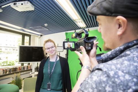 Henkilö kuvaa toista videokameralla studiotiloissa.