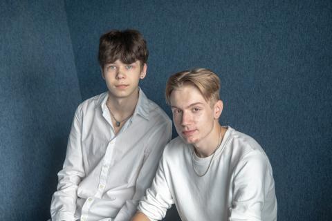 Kesäsomettajat istuvat sinisen taustan edessä ja katsovat kameraan.