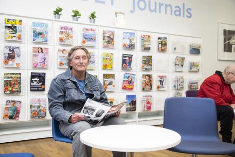Juhani Ylikorpula istuu kirjaston lehtilukusalissa lukemassa lehteä.
