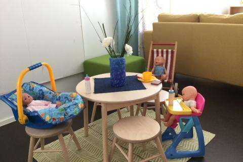 Little dolls sit around the table eating.