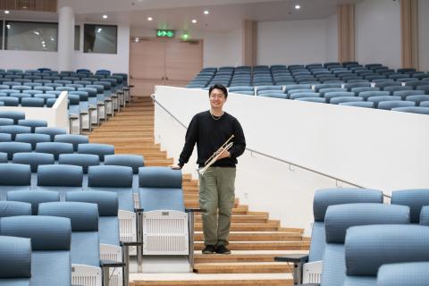 Principal trumpet player Xiang Guo stands in the Great Hall of Tampere Hall with a trumpet in his hands.