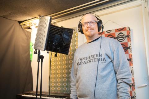 Niko Torvinen seisoo kuulokkeet päässä mikrofonitelineen luona.