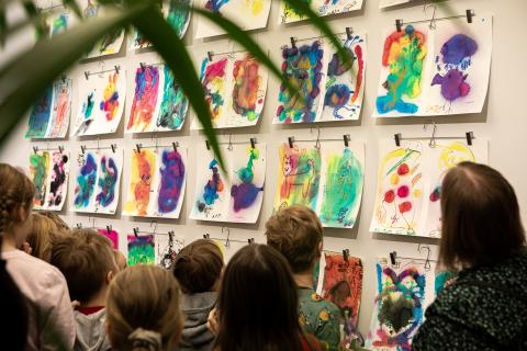 Lapsiryhmä katsoo värikkäitä taideteoksia.