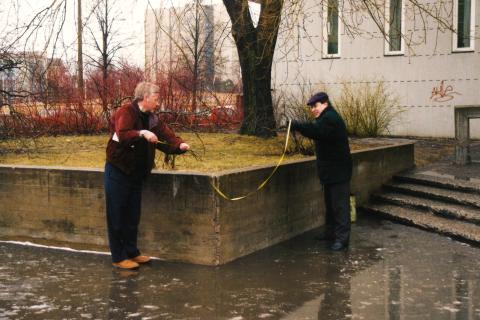 Kaksi henkilöä mittaa mittanauhalla Sampolan edustan betonirakennelmaa.